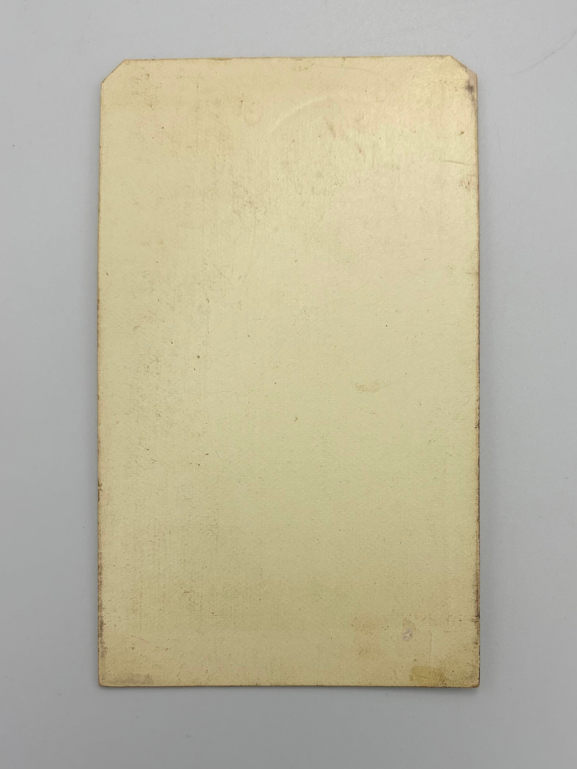 A blank, aged beige rectangular card with a slightly textured surface, photographed flat against a neutral gray background.