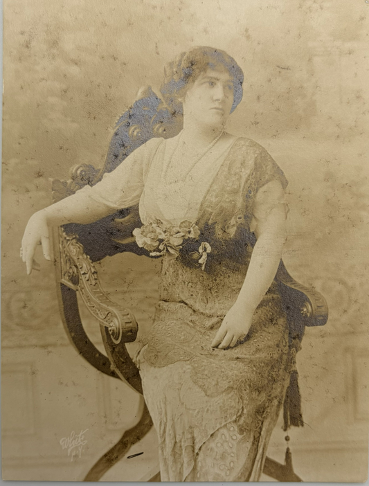 Vintage sepia-toned portrait photograph of a seated woman in an ornate chair