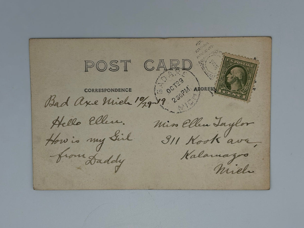 A vintage postcard with handwritten letters, a circular postmark, and a green postage stamp, displayed against a light gray background.