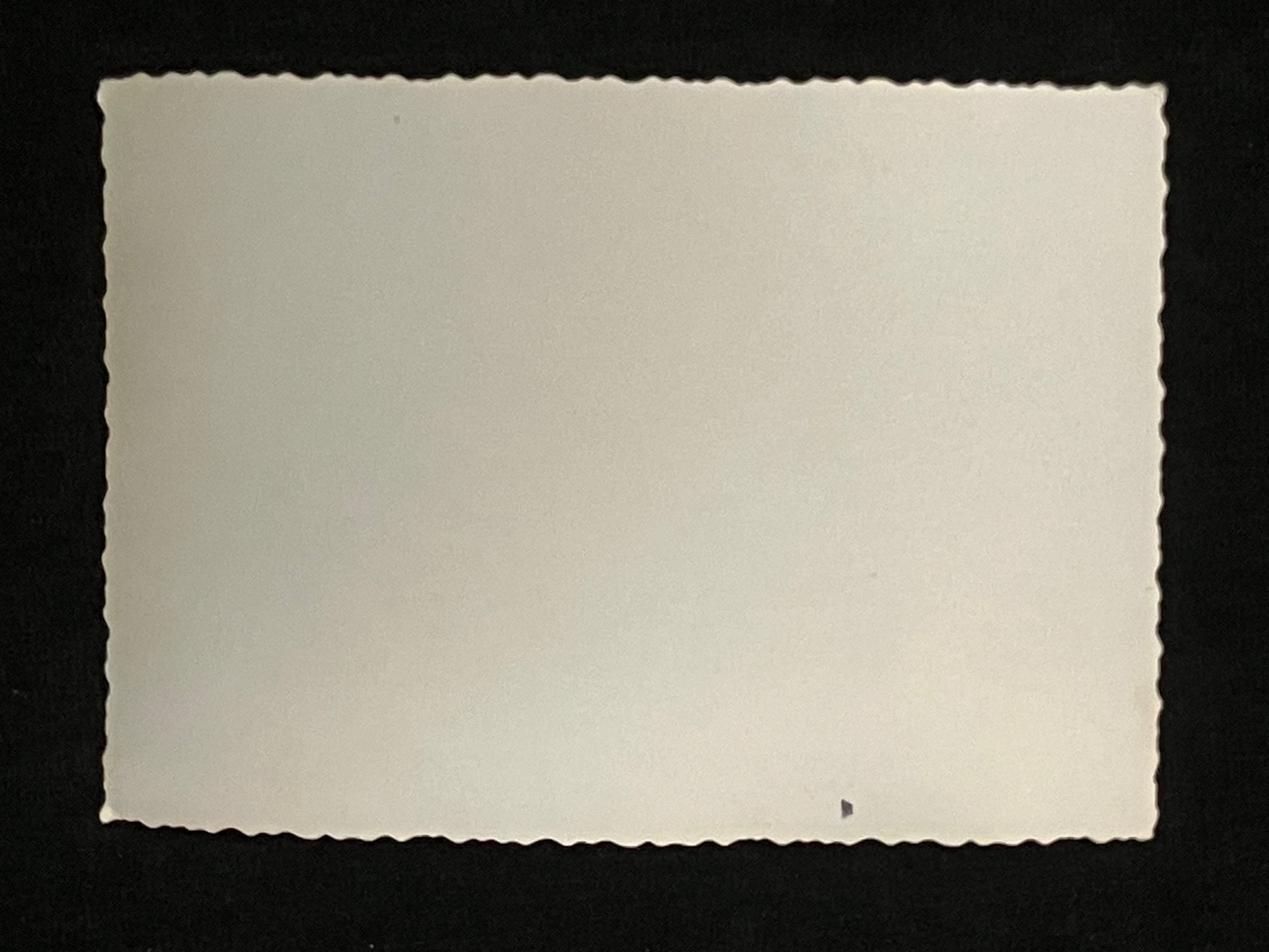 Rectangular white card with scalloped edge on a black background