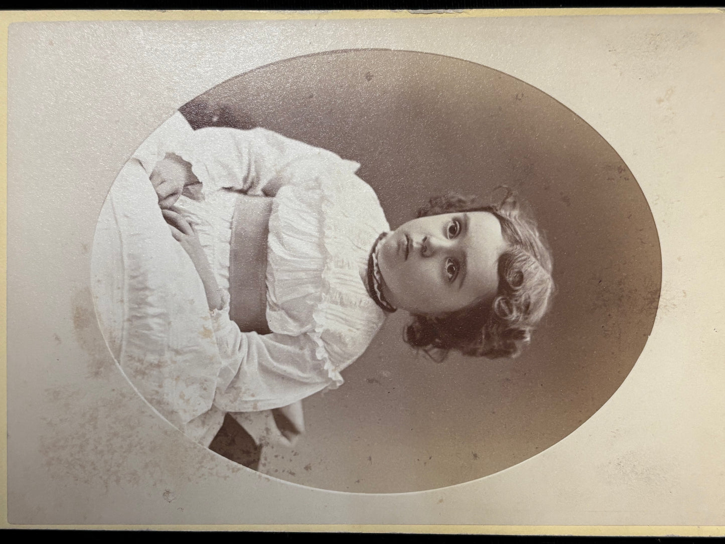 Vintage black and white portrait of a girl in a white dress with a large bow.