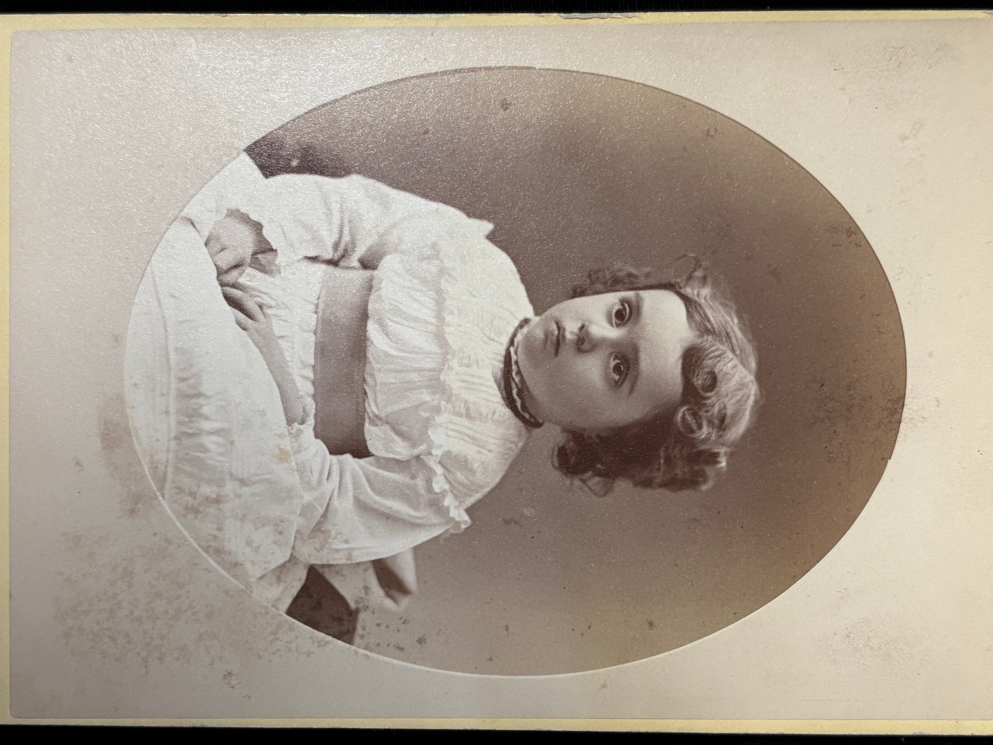 Vintage black and white portrait of a girl in a white dress with a large bow.