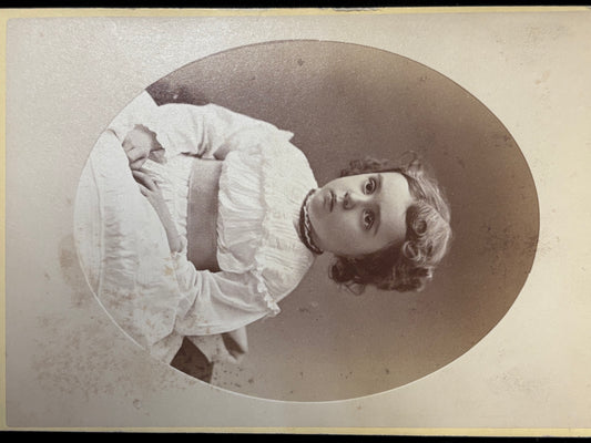Vintage black and white portrait of a girl in a white dress with a large bow.