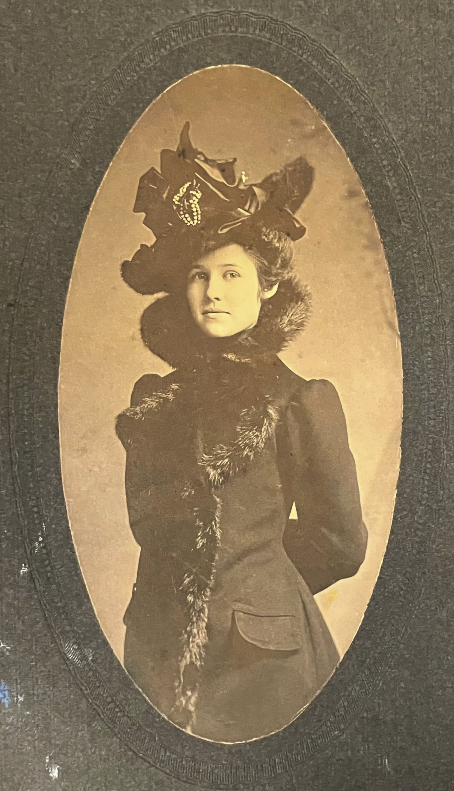 Vintage photograph of a woman wearing a decorative hat and coat with fur trim.