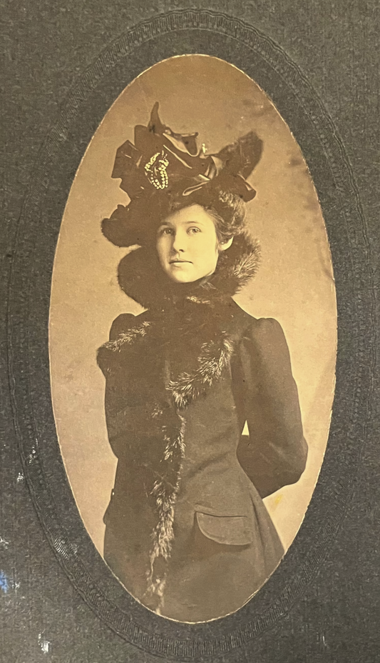 Vintage photograph of a woman wearing a decorative hat and coat with fur trim.