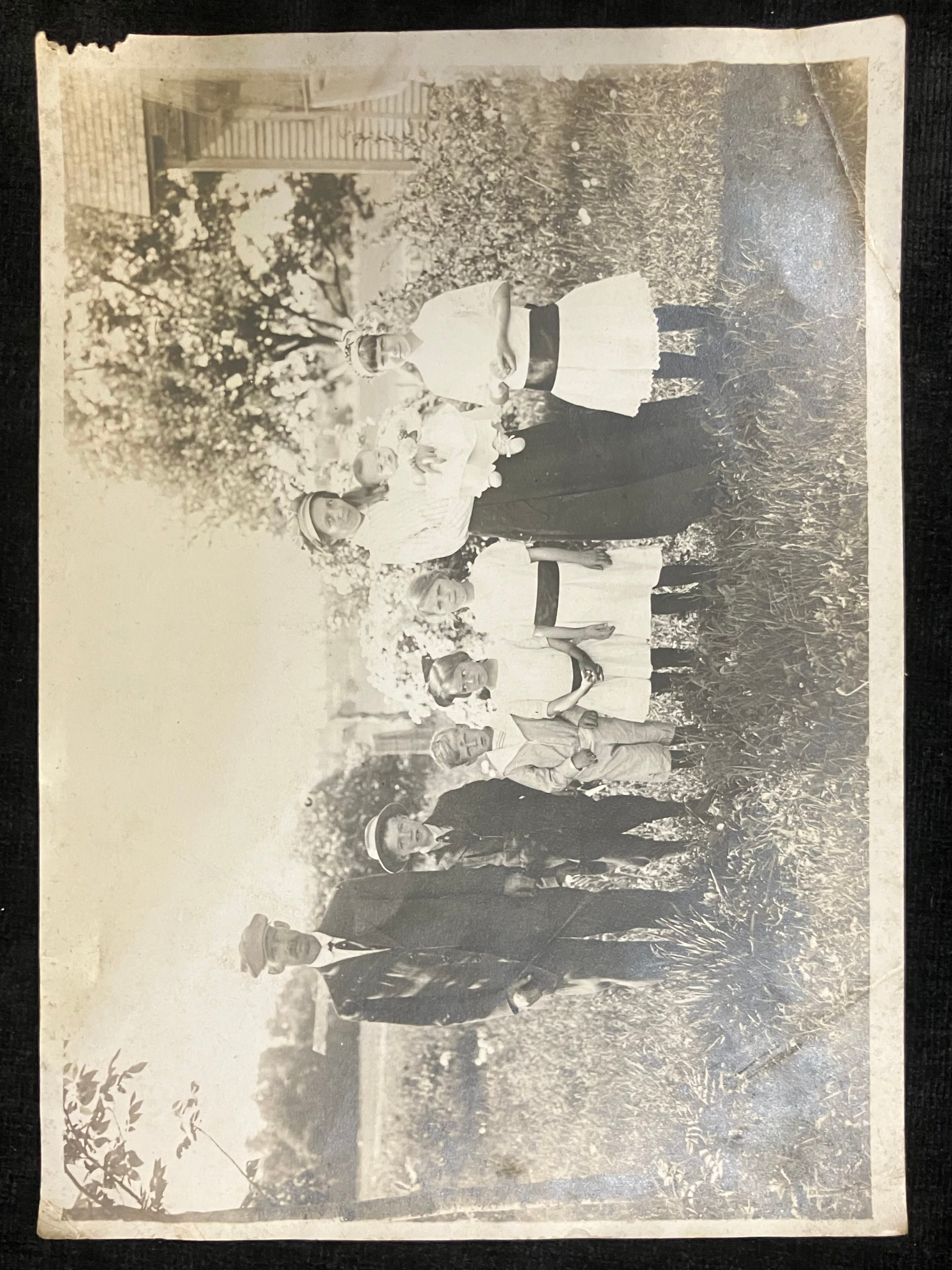 Vintage black and white photo of people outdoors with flowers in bloom.