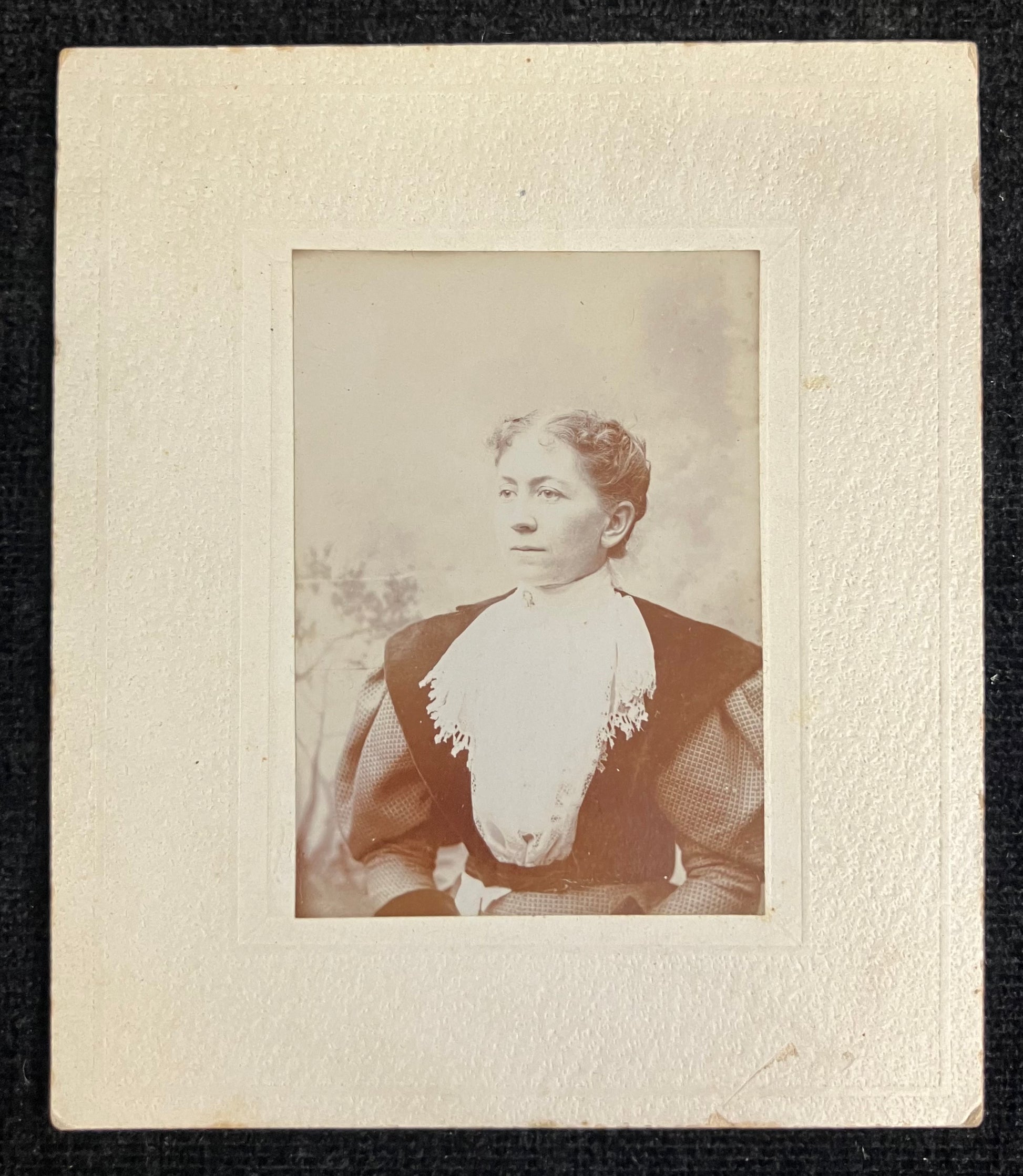 Vintage photograph of a woman with a decorative collar, framed by a textured border.