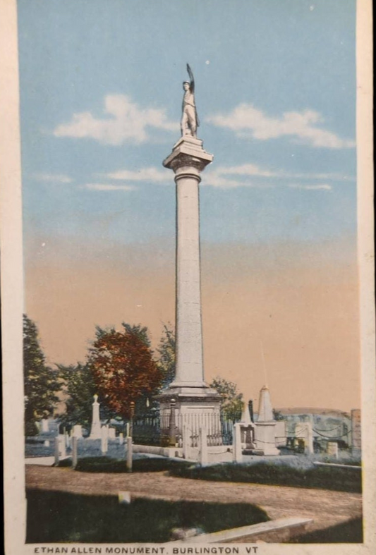 Ethan Allen Monument in Burlington, VT with a statue on top against a blue sky.
