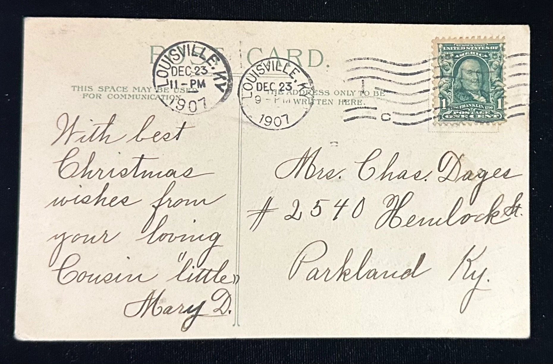 Vintage Christmas postcard with stamps and cursive writing, featuring a Christmas stamp on the back.