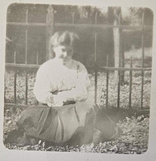 RPPC - Portrait of Smiling Teenage Girl - In Victorian Clothing by Iron Fence - Bashful Teen Posing in Bright Sunshine Real Photo Postcard