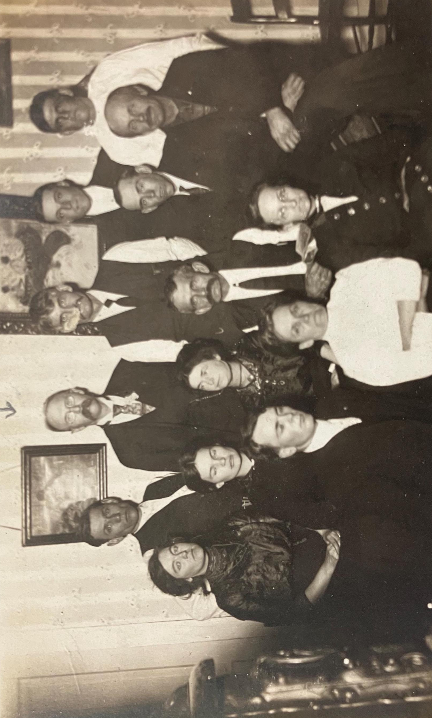 A black and white photo postcard featuring a group of 14 family members from the early 1910s, dressed in formal attire, gathered together for a family photo.