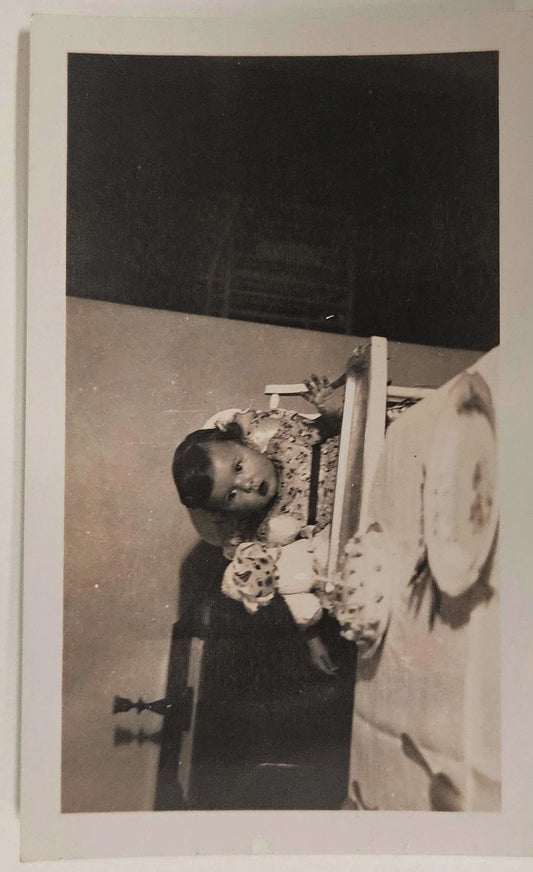 Photograph of Baby's First Birthday  - Late 1930s Real Photograph - Baby Girl in Highchair with Doll and Cake with one candle - Black and White Photo