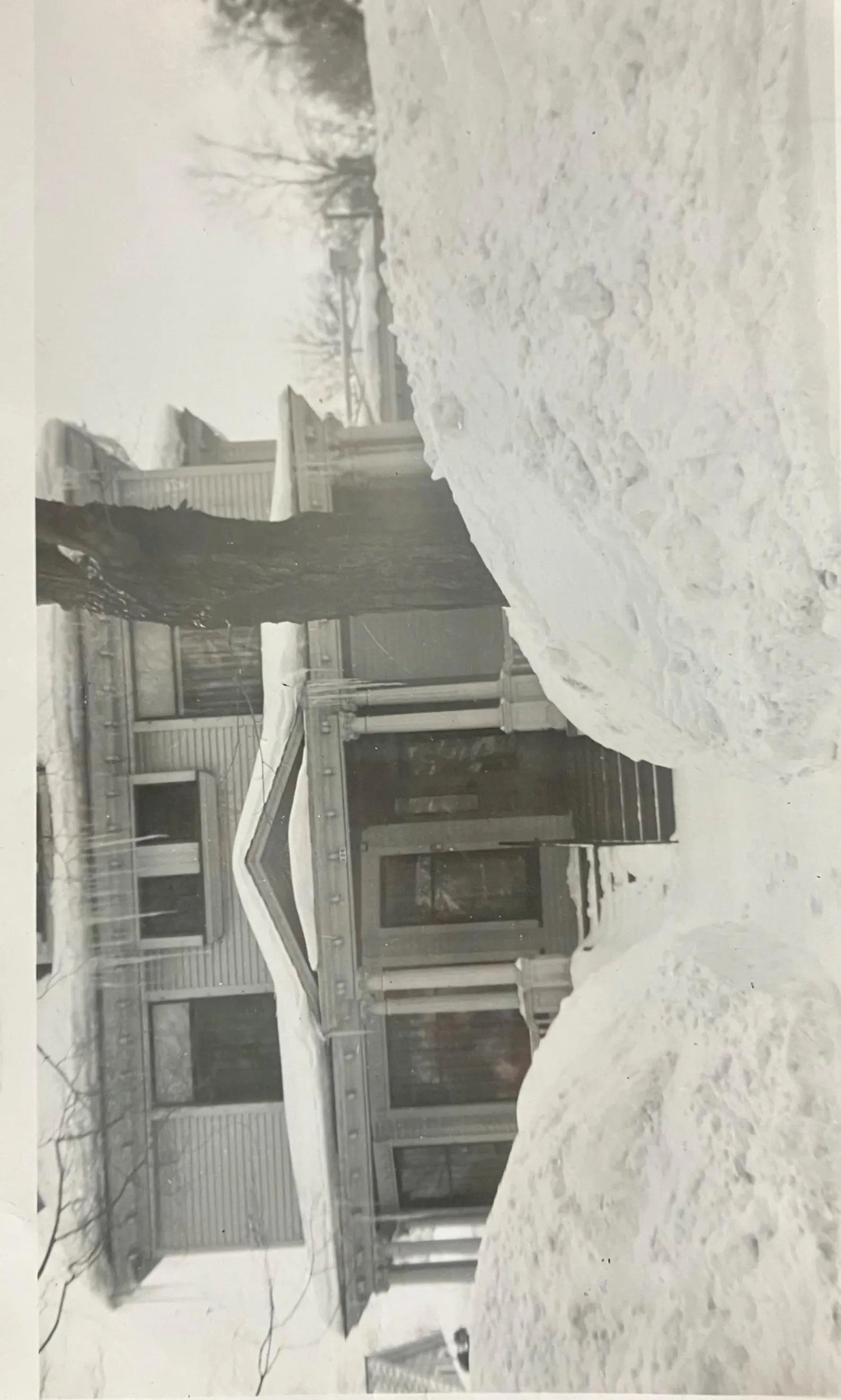 Black and white photo of a house partially buried in snow