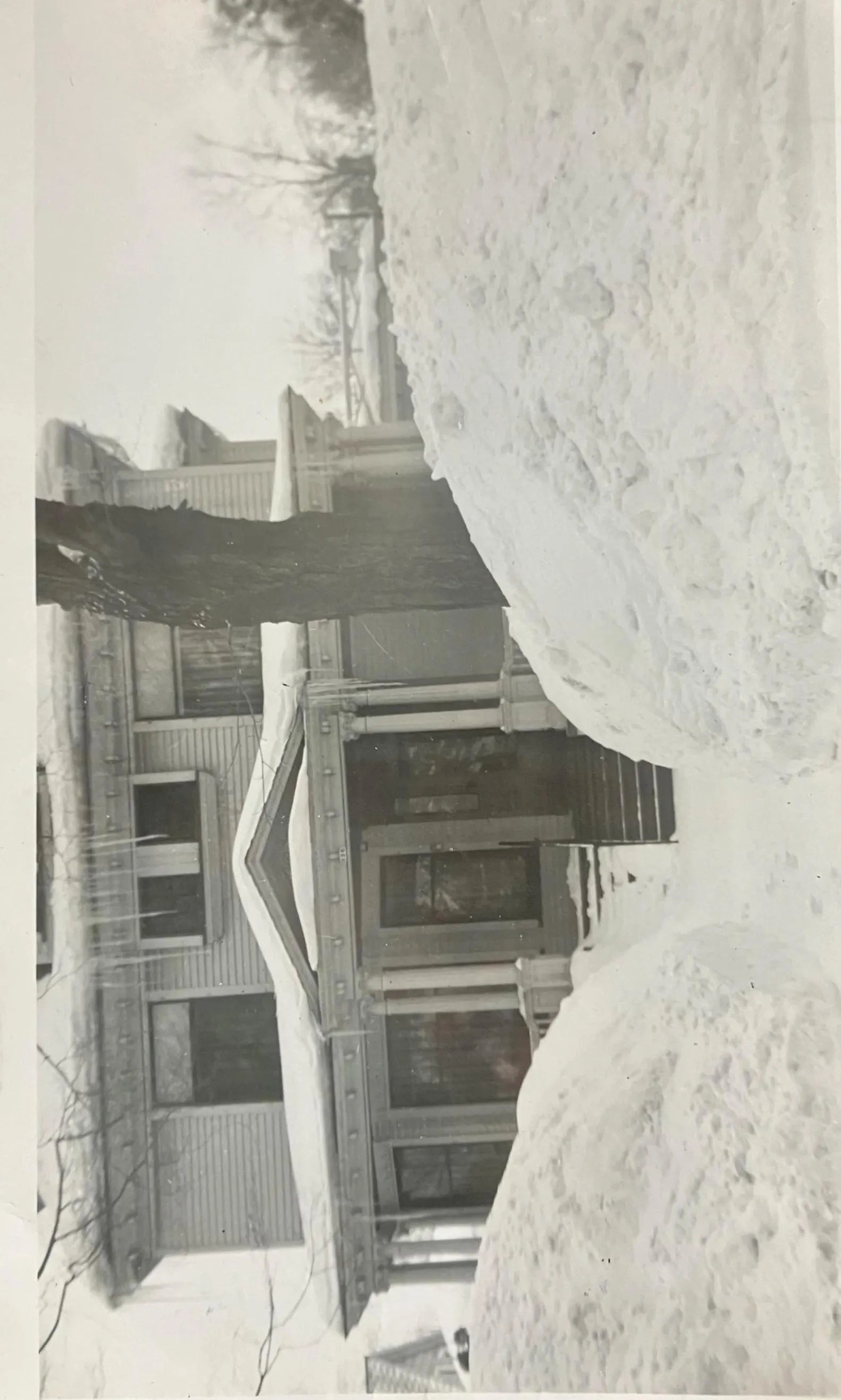 Black and white photo of a house partially buried in snow