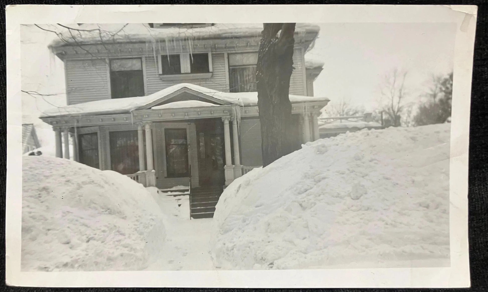 Vintage black and white photo of a house covered in snow