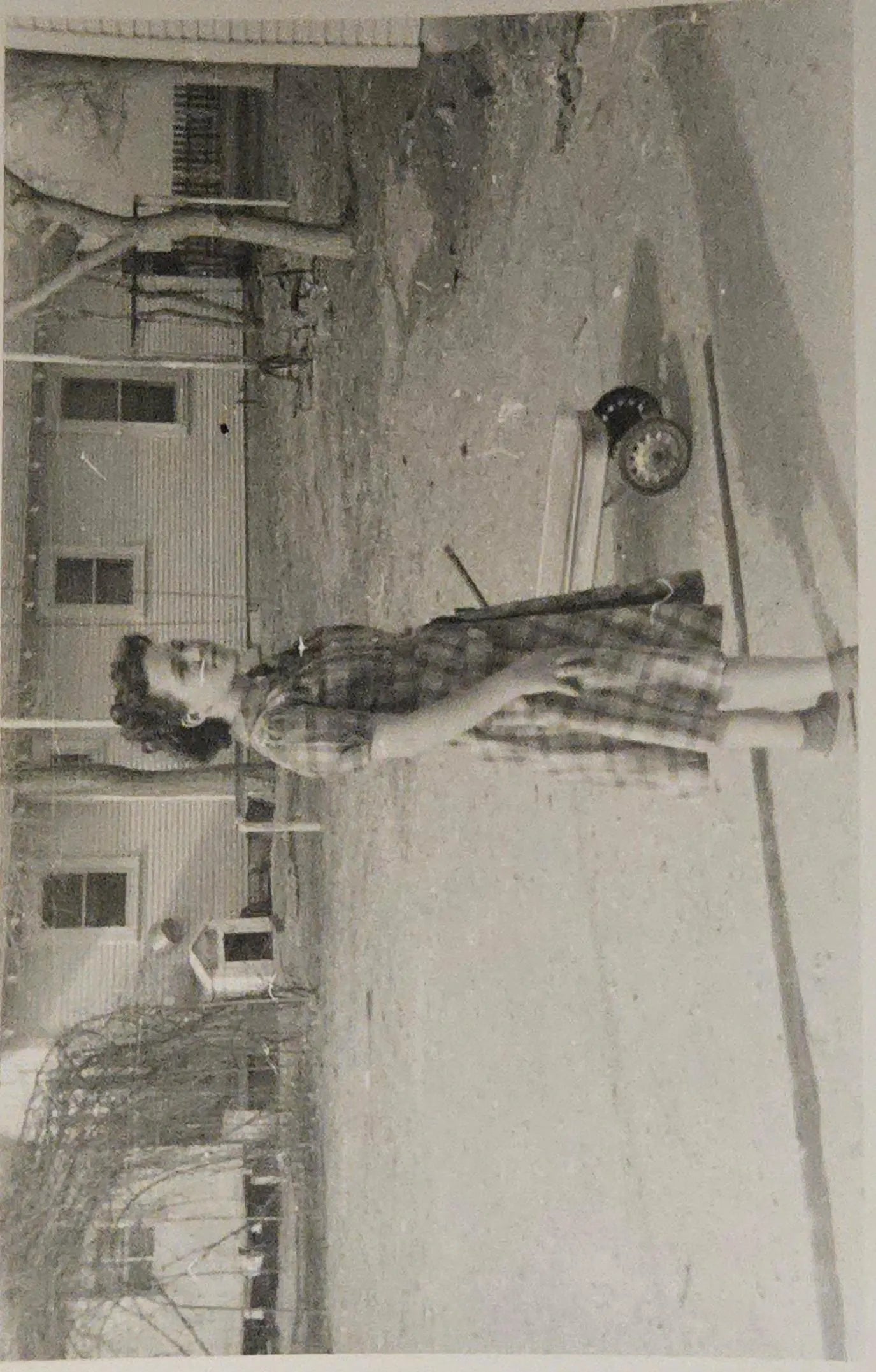 Vintage black and white photo of a person standing outdoors with a house in the background