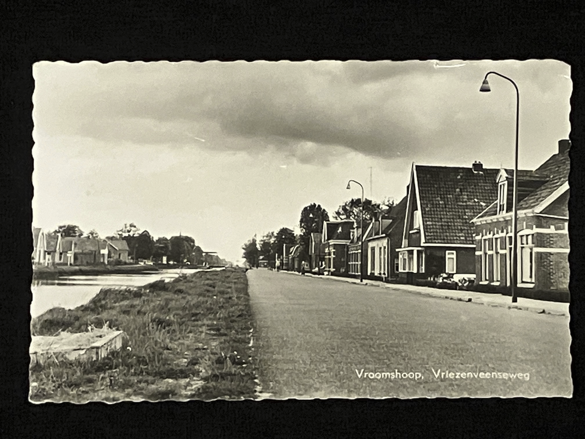 Vintage black and white photo of Dutch street Vriezenveenseweg with houses and a lamp post.