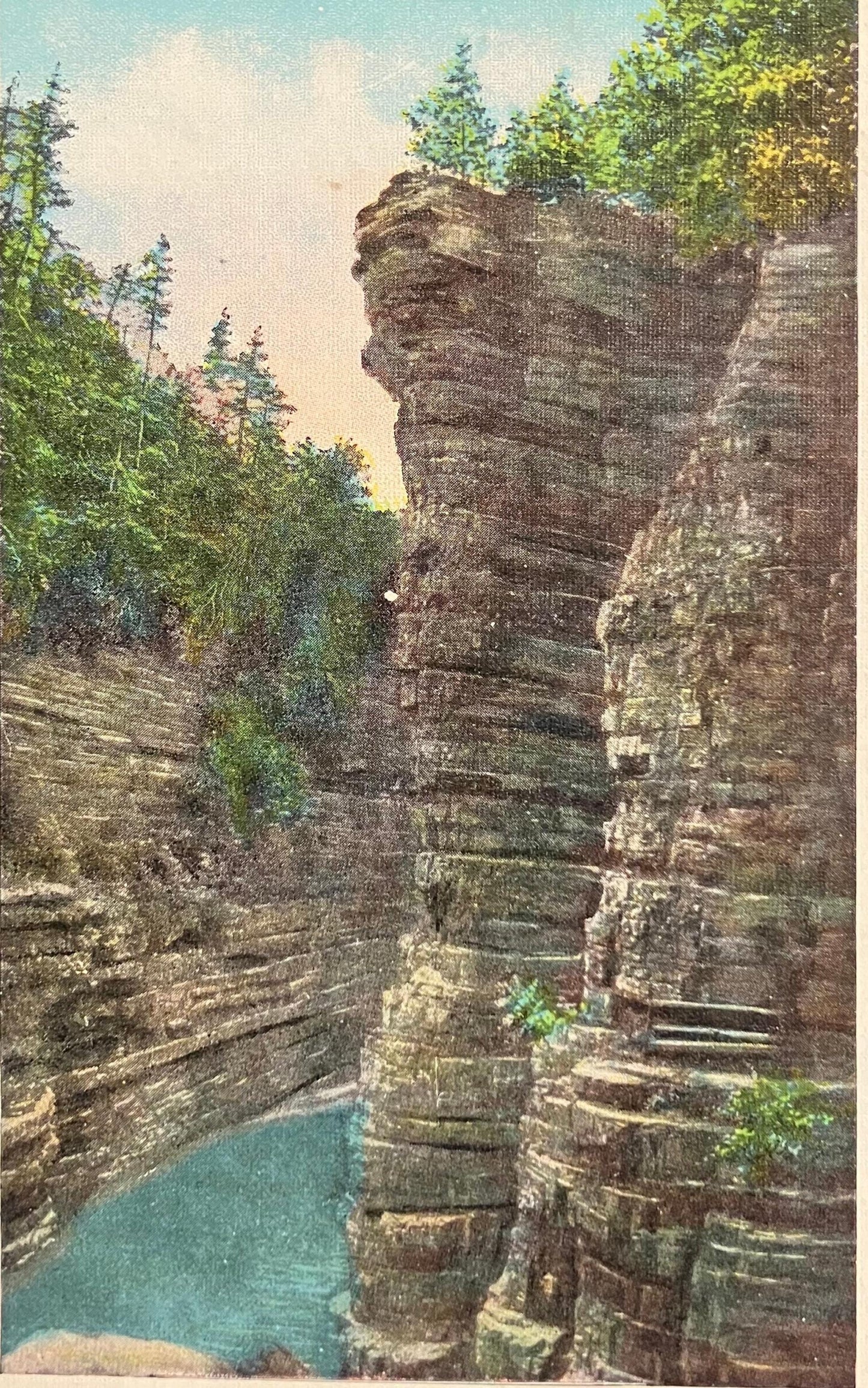Stunning natural rock formation with water at the base, surrounded by trees.